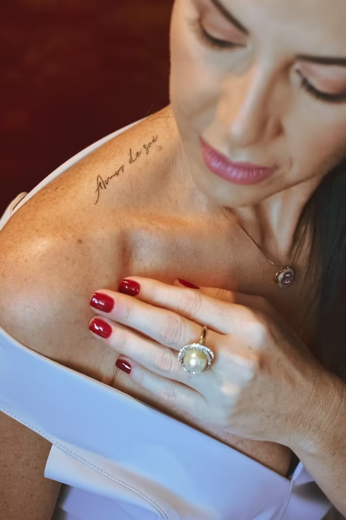 Detalhe íntimo — tatuagem 'Amor de si' representando autoestima e identidade